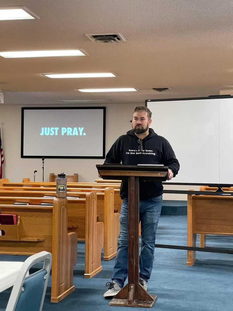 Kris teaching at the podium with a Just Pray slide